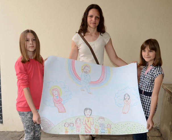 Marija, Ivana i veroučiteljica drže plakat nagrađenog crteža